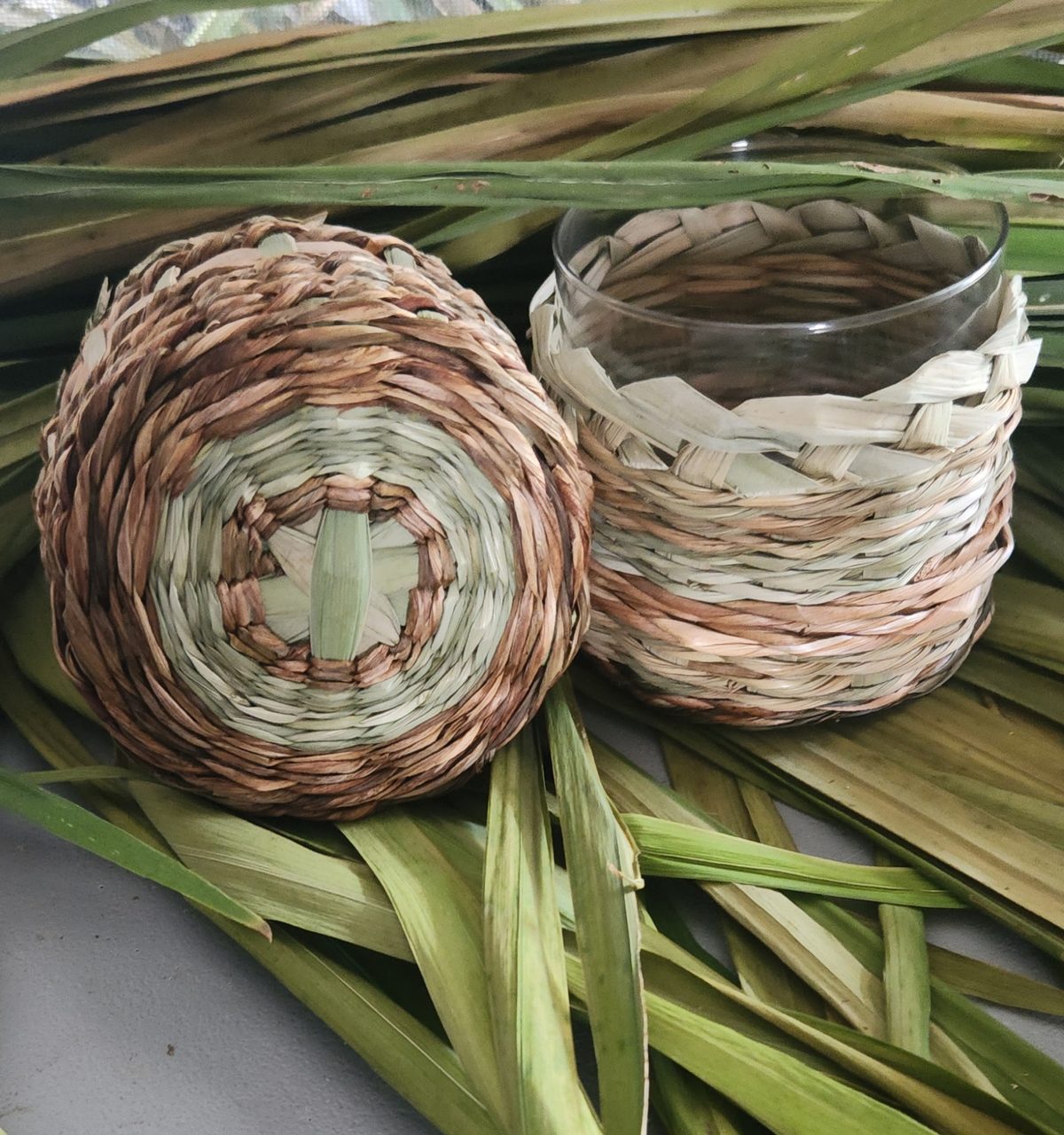 Two twined baskets resting on green palm leaves